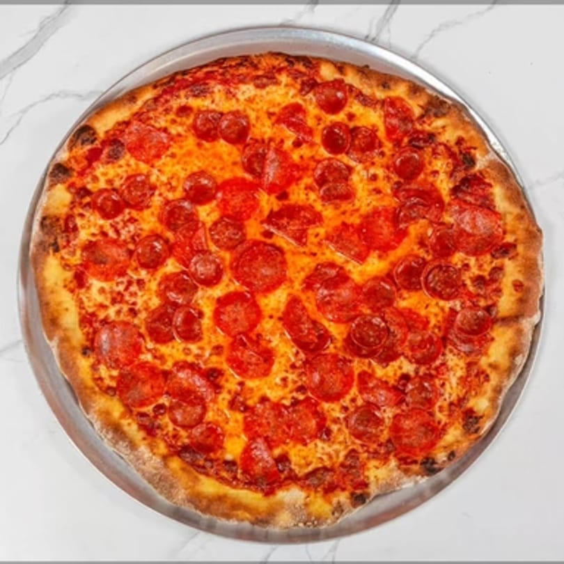 A whole pepperoni pizza from Big Oven Pizza Mobile Truck, on a metal tray, against a white marble background.