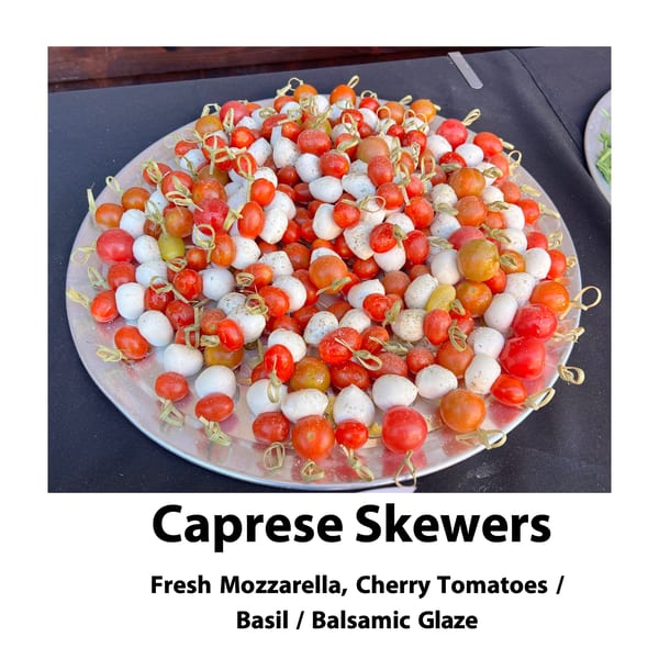 A silver platter filled with numerous Caprese skewers, featuring cherry tomatoes and mozzarella balls.